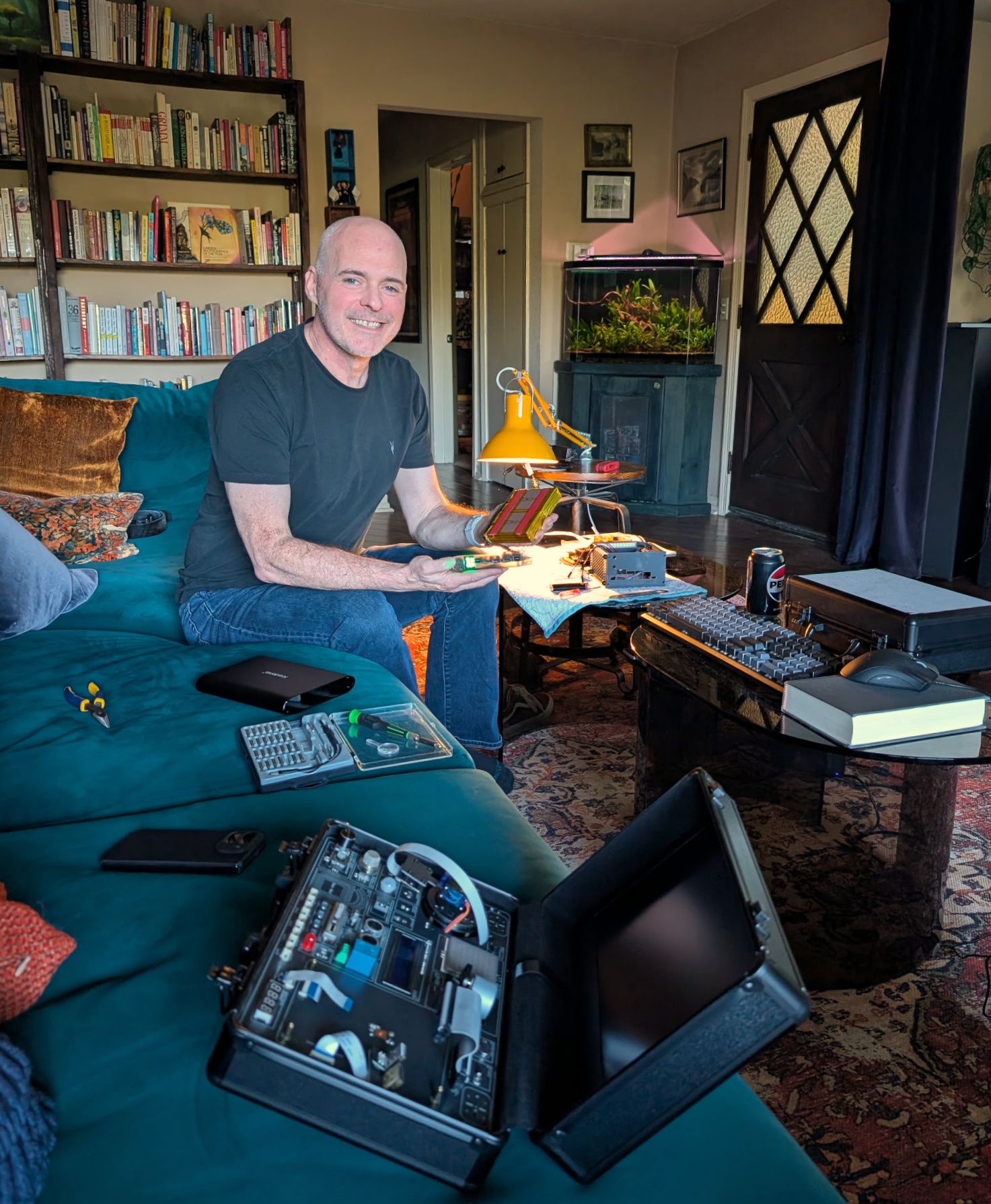 Jim Kunz sitting on a couch with Sparky and components spread out on the table